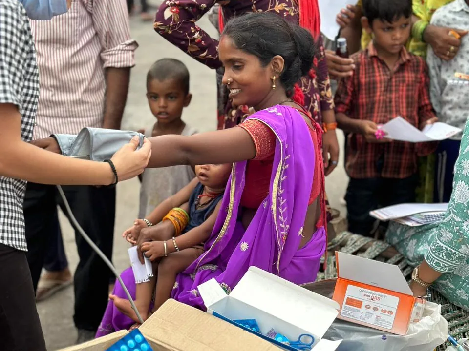 A volunteer checks a woman's blood pressure at a Tele-Upchaar health camp